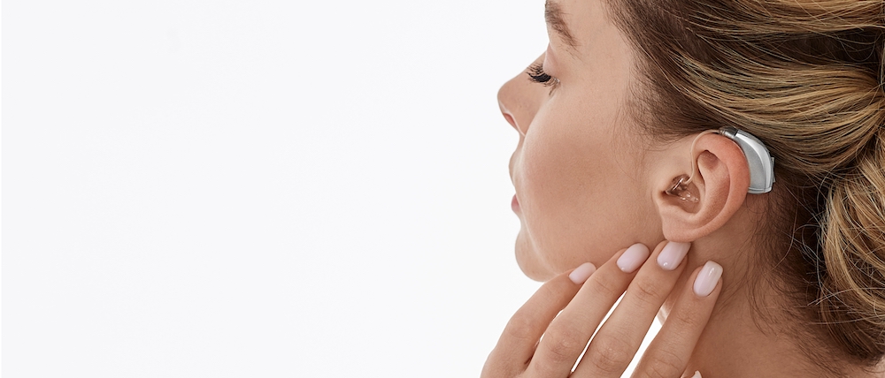 Hearing aids, hearing solutions. Woman enjoys a full life and can hear surrounding sounds thanks to a hearing aid behind her ear